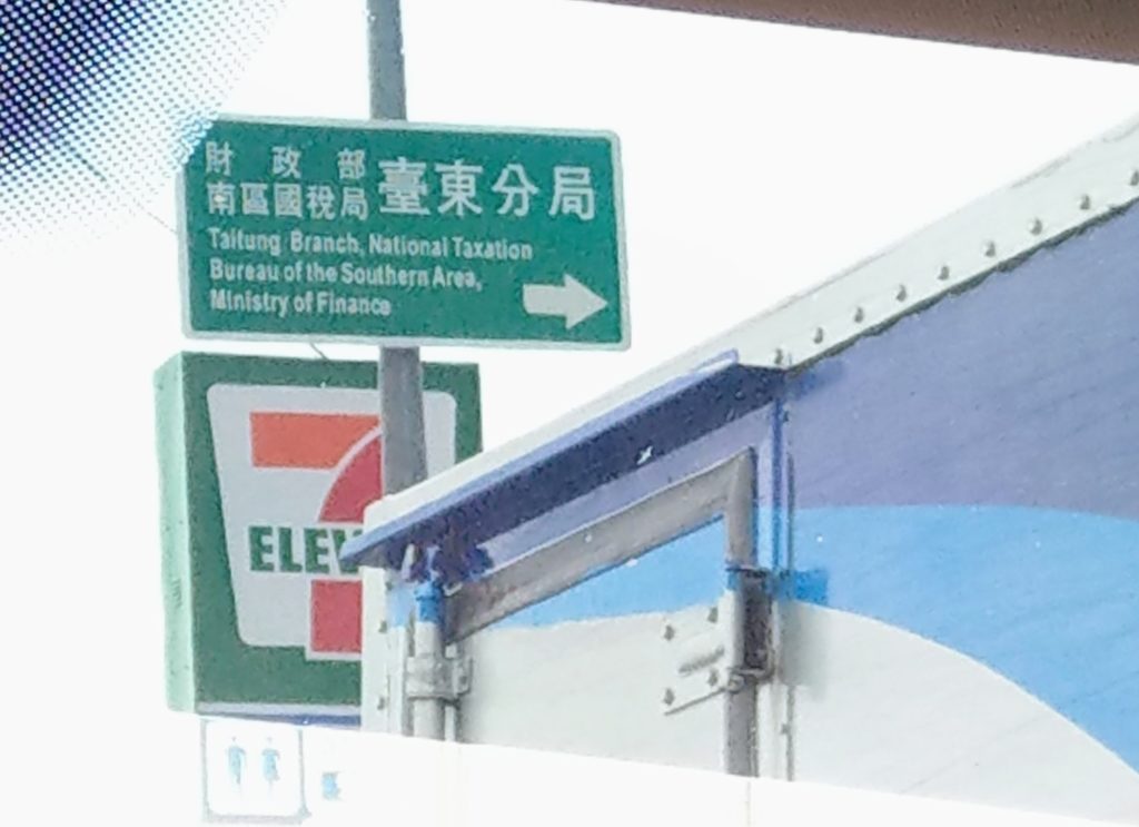 Directional road sign high on post. It reads (in Chinese characters) 'Caizhengbu, Nanqu Guoshuiju, Taidong Fenju' and (in English) 'Taitung Branch, National Taxation Bureau of the Southern Area, Ministry of Finance', as discussed in the post itself.