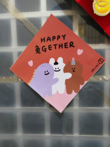 photo of a drawing on a door with three cartoon figures and text of 'HAPPY 兔GETHER'