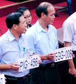 Taipei City councilors holding up signs resembling license plates with funny English: PIG-456 and EGG-008