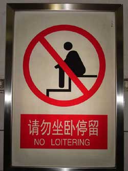 stylized image of a person sitting on a stair, with the caption 'no loitering' in English and Mandarin
