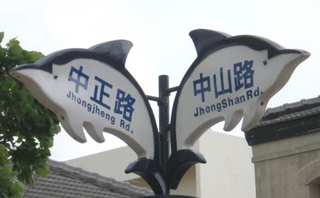 street signs reading 'JhongShan Rd.' -- note InTerCaPiTaLiZaTion -- (Zhongshan Road) and 'Jhongjheng Rd.' (Zhongzheng Road) -- no intercapping