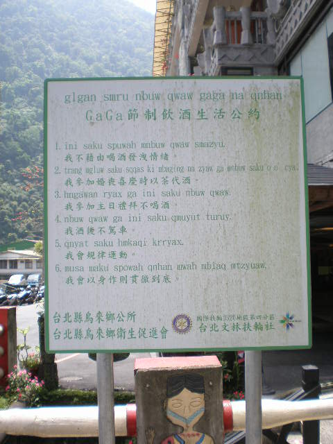 The top line reads 'glgan smru nbuw qwaw gaga na qnhan'. It's followed by 6 numbered points in romanized Atayal and then Mandarin in Chinese characters. Finally, it's identified as being from the local government as well as the Rotary Association and other groups.