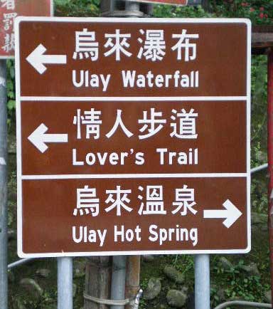 three brown (culture) signs with 'Ulay Waterfall', 'Lover's Trail', and 'Ulay Hot Spring', along with their respective Chinese characters