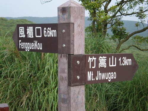 wooden directional signs reading '風櫃口 FenggueiKou' and '竹篙山 Mt.Jhwugao'