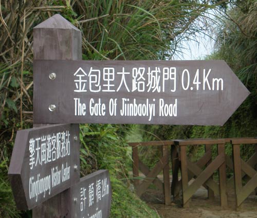 wooden directional sign reading '金包里大路城門 The Gate Of Jiinbaolyi Road'