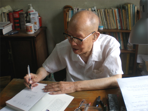 Hanyu Pinyin creator Zhou Youguang (???) at his desk, autographing a book