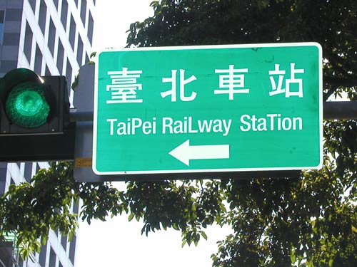 directional sign reading 'TaiPei RaiLway StaTion' (with a capital P in Taipei, a capital L in Railway and the second T capitalized in Station)