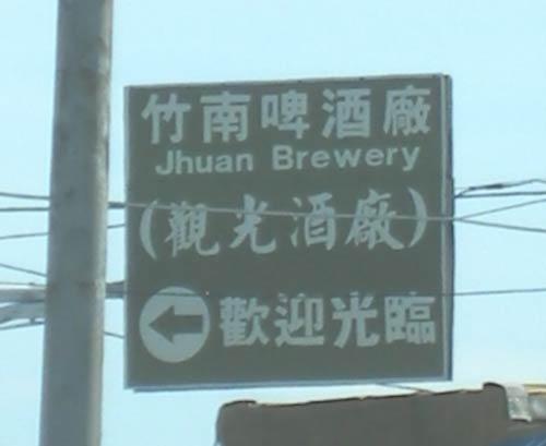 directional sign above the highway, reading 'Jhuan Brewery'