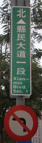 Xianmin Blvd. Sec. 1 (This is a vertical sign, too narrow for 'Xianmin' on one line, so it's hyphenated, with 'min' on the second line)