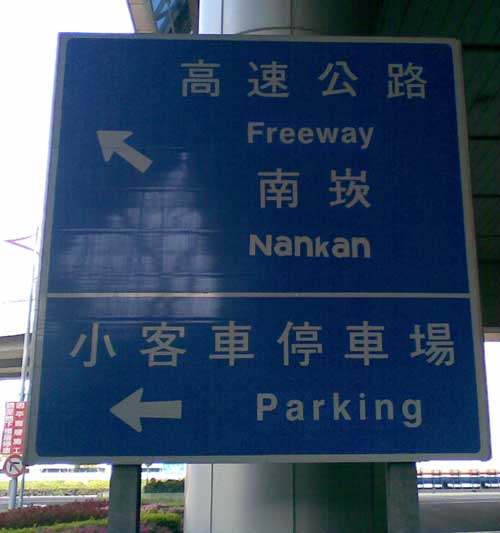 a directional sign pointing the way to Nankan -- but 'Nankan' is written with all letters the same height (i.e., the capital 'N' is reduced to the height of the letter 'a' and the 'k' is similarly shrunken)