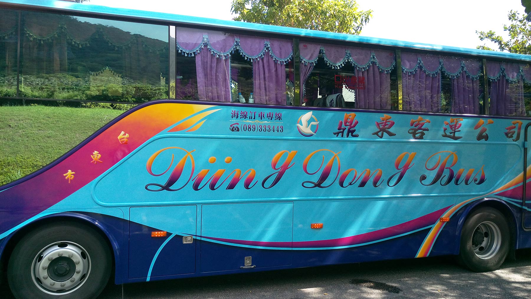 photo of a coach bus, with 'Diing Dong Bus' in large letters on the side, with the bottom of the descenders on the g's sitting on the baseline